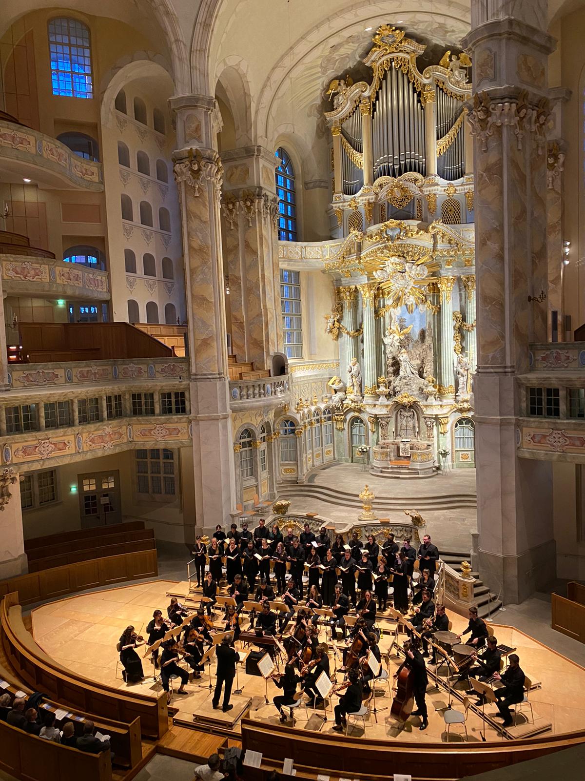 A group of students performing in an ornate baroque church sanctuary