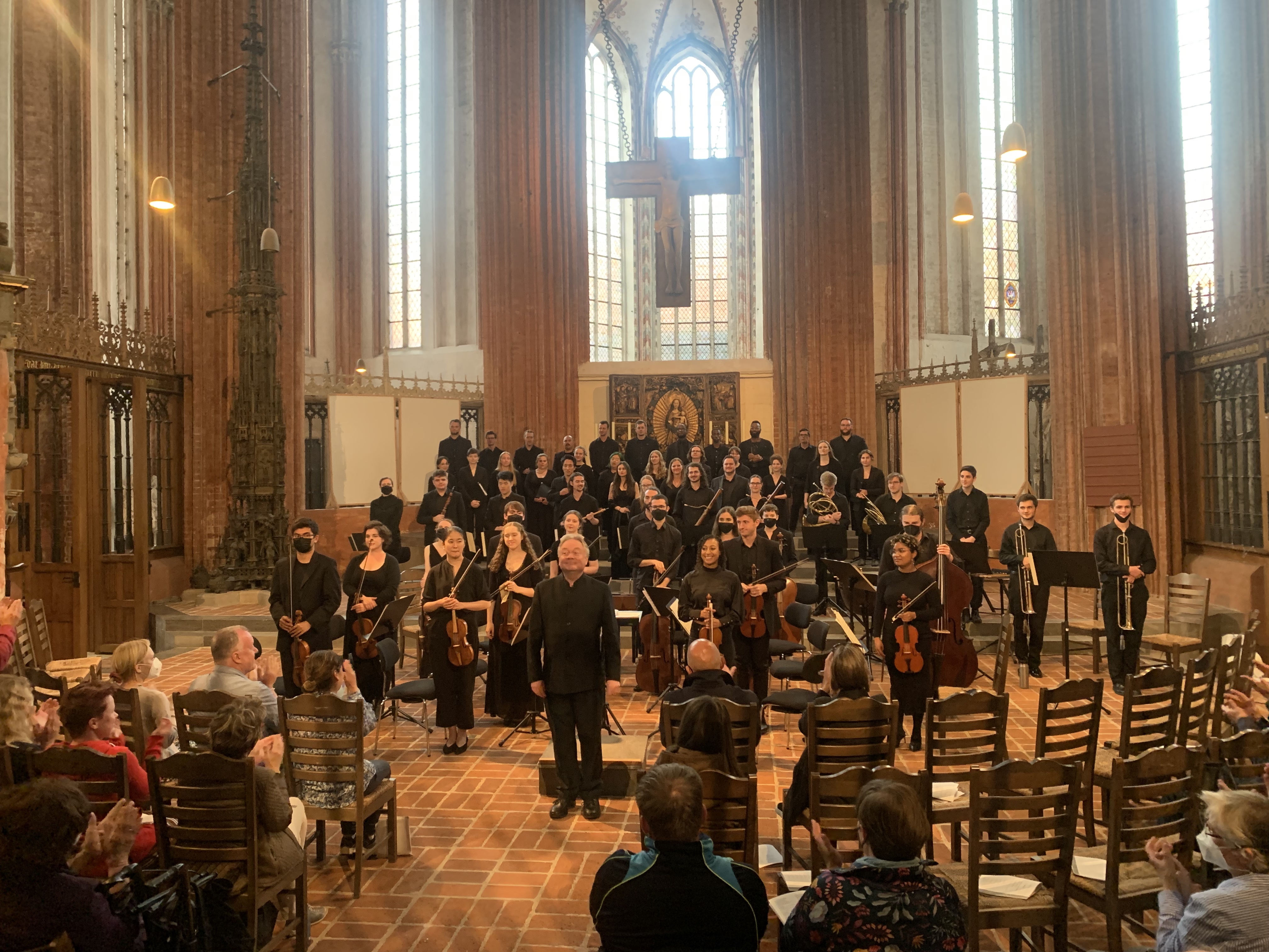 The ensemble stands for an ovation after a performance in a church sanctuary